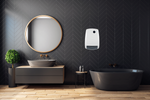 A sleek white wall-mounted electric heater provides warmth in a modern bathroom featuring dark grey chevron tiles, a wooden floating vanity, and a black freestanding bathtub.
